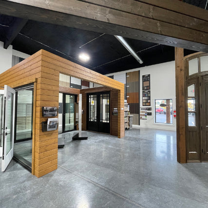 DoorsModern showroom interior featuring a wood-paneled display of sliding glass doors. Nearby walls showcase various door samples. Bright, contemporary ambiance.